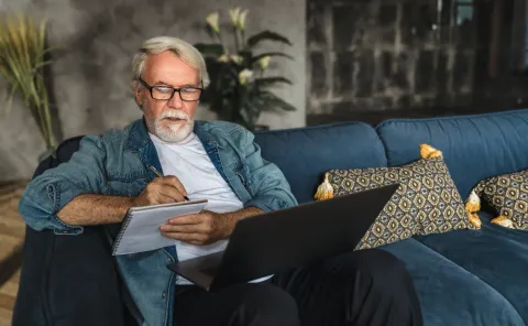 Man taking notes while watching a webinar