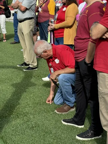 Roger Helmrichs, Delaware County Extension Council, kneels down to feel the turf.