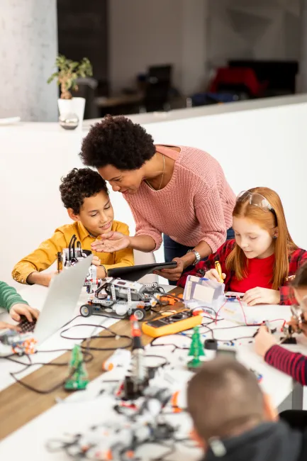 An adult teaching children about electric circuits