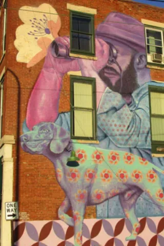 Mural of a man looking through binoculars painted on a brick building