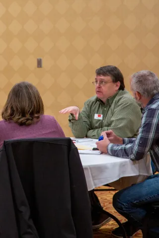 Three extension council members in conversation around a table 