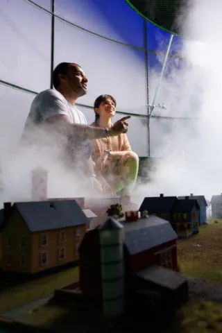 Professor with student viewing the airflow around a model town in a tornado simulator